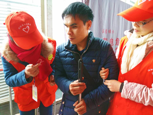 重庆 火车北站春运志愿者帮助盲人旅客进站
