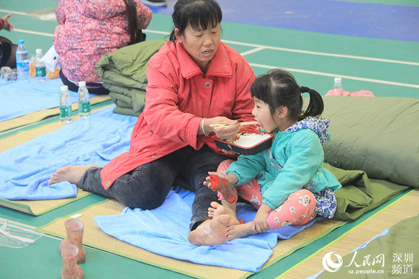 深圳光明新区群众体育中心安置点，家长喂小孩吃饭。（光子健 摄）
